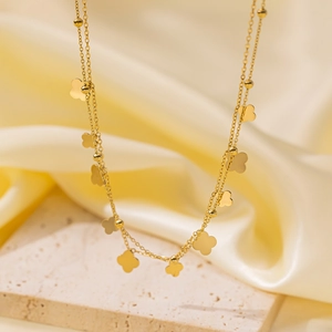 Detailed shot of 18K gold-plated titanium clover charms and beads on layered chain