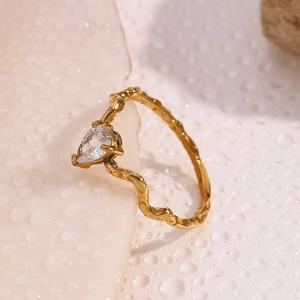 Macro detail of snake-shaped gold ring with pear-cut crystal and textured band