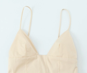 Detail of light beige poplin midi dress with thin straps and deep V-neckline stitching