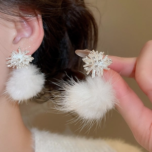 Close-up of white plush pompom earrings with silver snowflake zircon studs for women