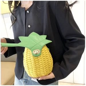 Close-up of handmade woven pineapple crossbody bag with green leaf lid and gold lock