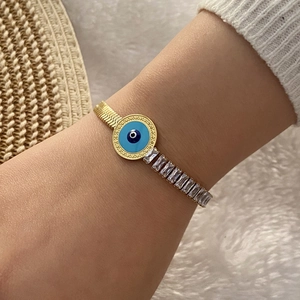 Detail of gold evil eye bracelet with blue enamel and cubic zirconia on wrist