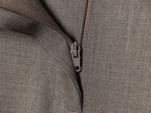 Macro shot of high-density brown-grey woven fabric texture and closed metal zipper detail