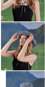 Detail of checkered sun hat with tie strap shown against a scenic outdoor mountain backdrop