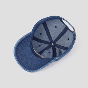 Detail of blue washed denim baseball cap interior showing seams and adjustable metal buckle