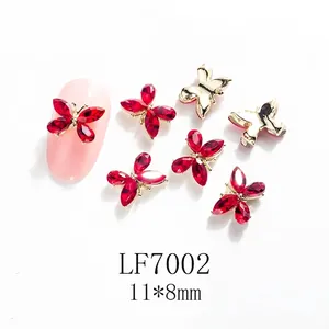 Detalle de dijes para uñas con lazo de diamantes rojos y base dorada de 11x8mm