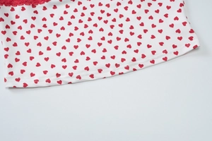 Détail du tissu à imprimé fleuri avec bordure en dentelle rouge et motifs cœurs