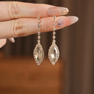 Close-up of golden tassel earrings featuring teardrop crystals and sparkling rhinestones