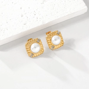 Elegant gold square pearl earrings with rhinestones on a white minimalist stone base