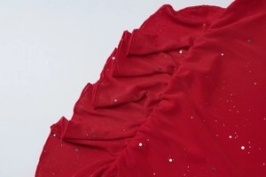 Close-up of red mesh fabric featuring silver sequins and elegant ruffled hem details