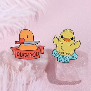 Humorous enamel banana duck pins with funny text and knife on soft pink background