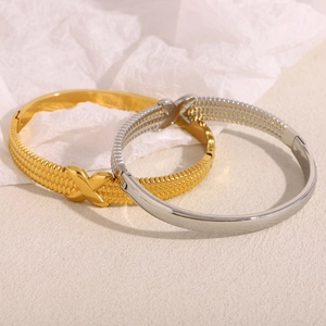 Detail of 18K gold and silver plated stainless steel bangles with X-pattern texture