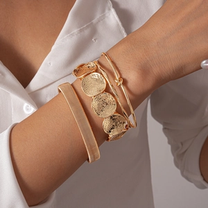 Detail of gold geometric metal bracelets set with hammer pattern on a female wrist