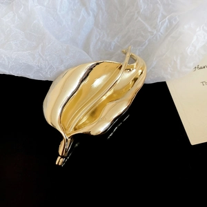 Macro detail of a high-quality gold metal leaf brooch with elegant curved textures