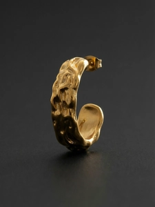 Macro view of gold-tone C-shaped hoop earrings with unique hammered textured surface