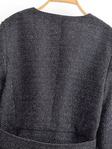 Close-up of the back tailoring and tweed fabric texture of the black fashion jacket