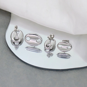 Macro shot of silver coffee bean earrings showing mirror polish on a reflective surface