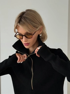 Detail of black ribbed knit sweater featuring silver zipper and cozy stand collar design