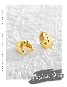 Close-up of gold-plated teardrop earrings with a high-shine mirror finish on white paper