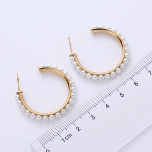 Macro shot of 3.5cm C-shaped gold pearl earrings with ruler for size measurement