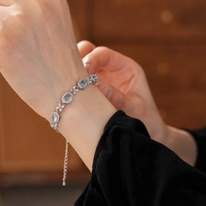Detailed close-up of a silver zircon flower bracelet with oval blue gemstones on wrist