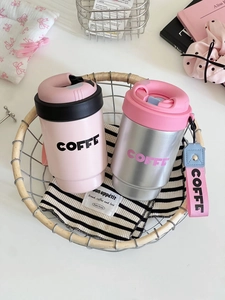 Close-up of pink and silver stainless steel coffee tumblers with strap on a tray