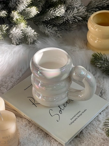 Close-up of pearl white ceramic mug with tiered rings on a cozy white plush background