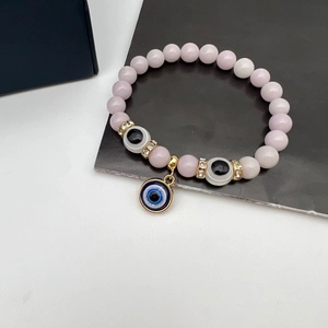 Macro detail of pink crystal beads with blue evil eye pendant and gold crystal spacers