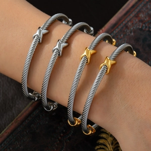 Retro stainless steel cable twist bangles with gold X accents on a female wrist