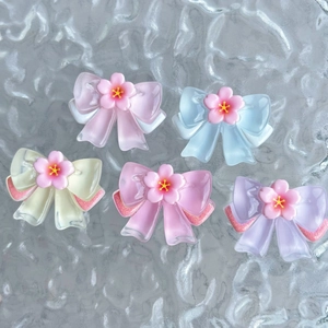 Macro shot of five colorful translucent resin bow charms with central floral details