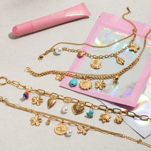 Détail de bracelets dorés multicouches avec perles et breloques oeil sur surface grise