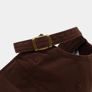 Detail of adjustable strap with bronze metal buckle on dark brown cotton baseball cap