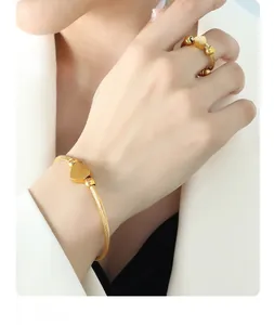 Detail of adjustable twisted gold wire bangle and heart ring set on white background