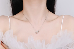 Gros plan d'un collier en argent S925 avec cœurs entrelacés porté par un mannequin