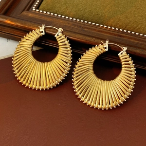 Macro shot of gold semi-circle earrings with radial texture on a vintage leather background