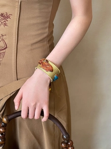 Detail of vintage matte gold open cuff bracelet with ethnic patterns on a model's wrist