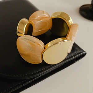 Detail of wide stretch bracelet with gold metal and marble resin on black leather