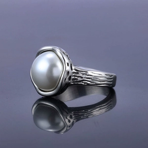 Minimalist stainless steel pearl ring with vintage tree bark texture on a dark background