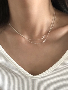 Close-up of a double-layered silver H letter pendant necklace on a female model