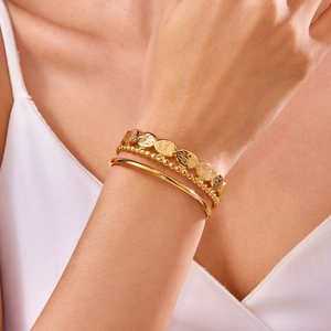 Close-up of three-piece gold-toned bracelet set featuring textured discs and polished bangle