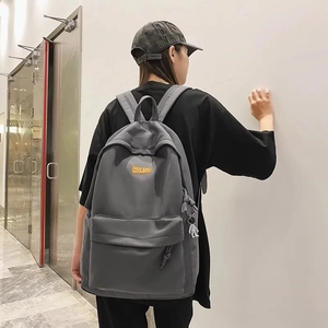 Detail of grey large capacity backpack with COOLBOY logo and side pendant on male model