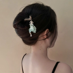 Detail view of a model wearing a bronze wood hair stick with a translucent fish tassel