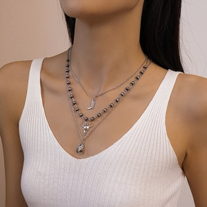 Close-up of triple-layered silver necklace with cowboy hat, boots, and bull skull charms