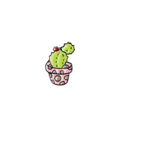 Close-up of a cactus enamel pin in a pink polka dot pot with a small red flower detail