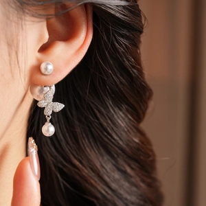Close-up of vintage gold-plated butterfly and pearl earrings worn by a model