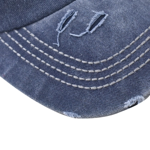 Dettaglio della visiera in cotone lavato con fori consumati e cuciture decorative