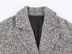 Détail macro du col d'un manteau en laine chevron avec texture et doublure noire