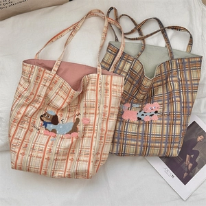Detail of plaid canvas tote bags featuring embroidered dog and cat patches with nice lucky text