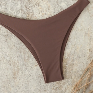 Detailed view of dark brown high-cut bikini bottom on textured stone background