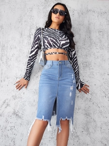 Close-up of zebra print crop top and distressed light blue denim midi skirt with frayed hem